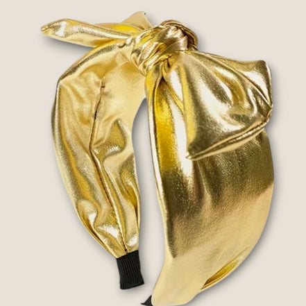 Foute haarband goud metallic met strik op beige achtergrond