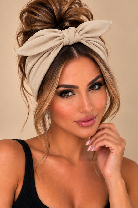Beige elastische haarband met strik gedragen door model - De HaarBoetiek