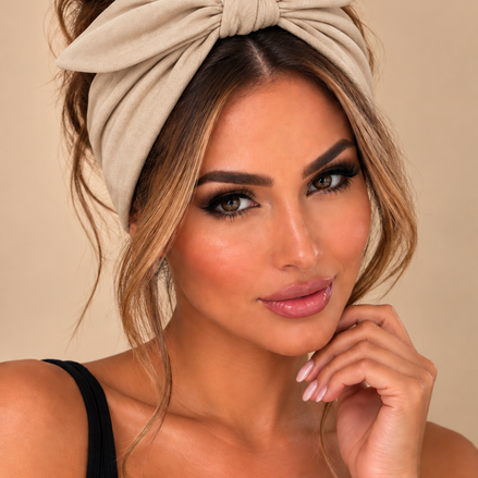 Beige elastische haarband met strik gedragen door model - De HaarBoetiek