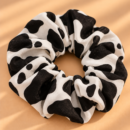 Zwart-witte koeienprint scrunchie op beige achtergrond