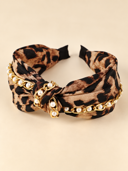 Luipaardprint knoop haarband met parels en goudkleurige ketting op egale beige achtergrond
