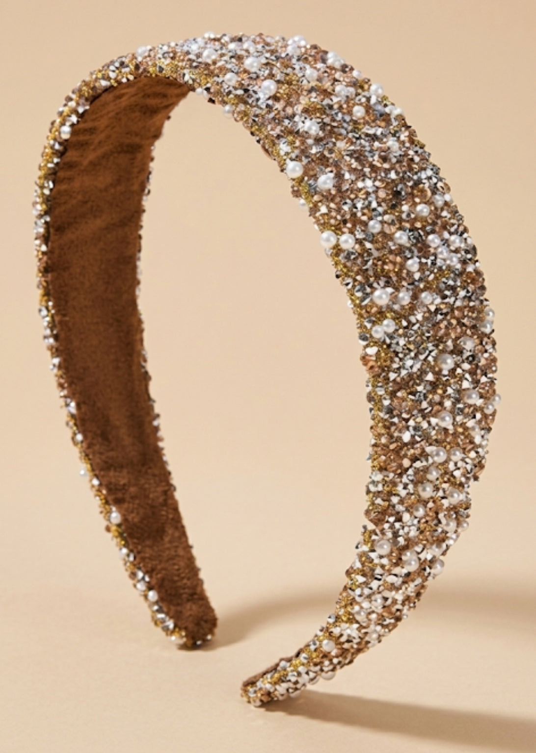Brede goudkleurige glitter haarband met strass en witte imitatieparels op beige achtergrond