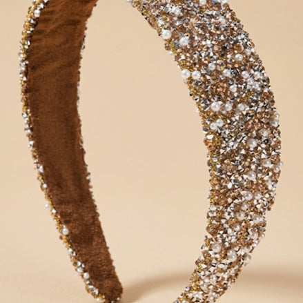 Brede goudkleurige glitter haarband met strass en witte imitatieparels op beige achtergrond