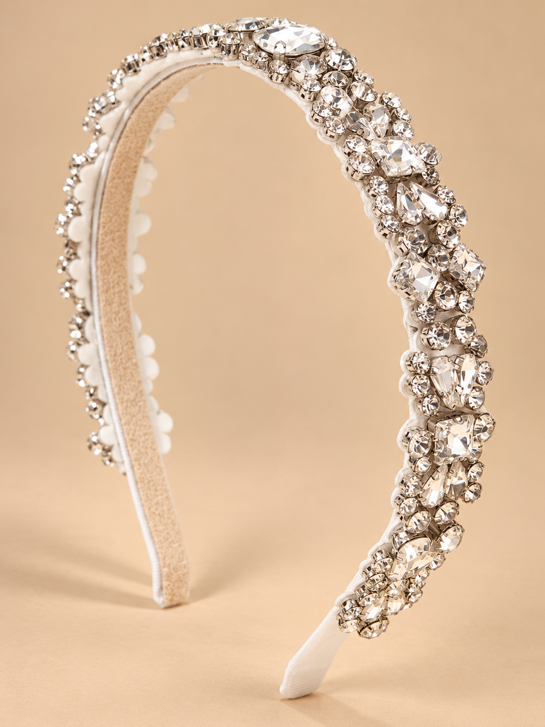 Luxe witte bruids haarband met heldere kristallen op beige achtergrond