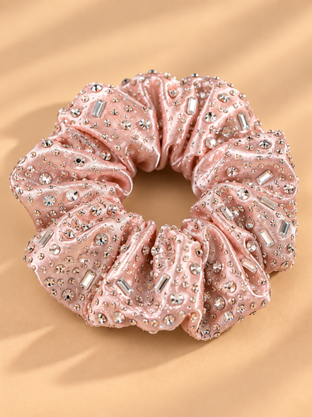 Luxe lichtroze scrunchie met strass steentjes op beige achtergrond