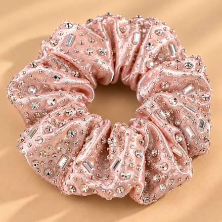 Luxe lichtroze scrunchie met strass steentjes op beige achtergrond