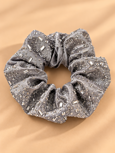 Luxe zilvergrijze scrunchie met strass steentjes op beige achtergrond