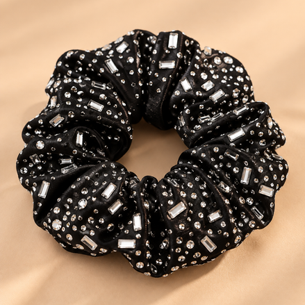 Luxe zwarte scrunchie met ronde en langwerpige strass steentjes op beige achtergrond