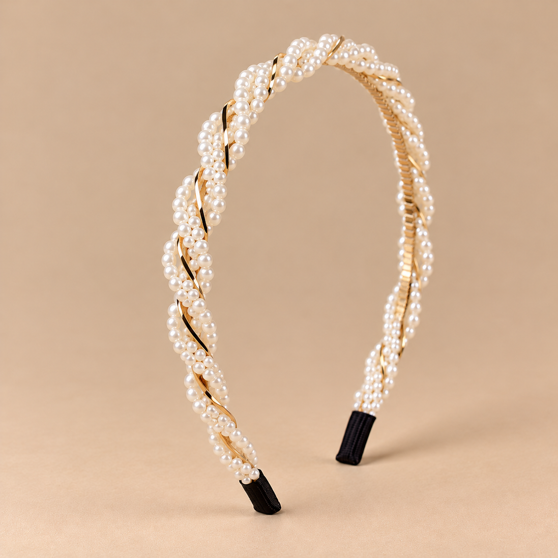 Gedraaide parelhaarband met ivoorkleurige imitatieparels en goudkleurige details op beige achtergrond