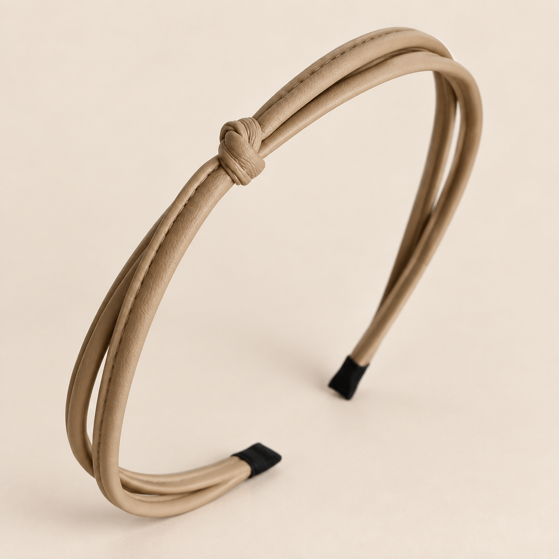 Smalle dubbele khaki haarband van imitatieleer met knoop op beige achtergrond