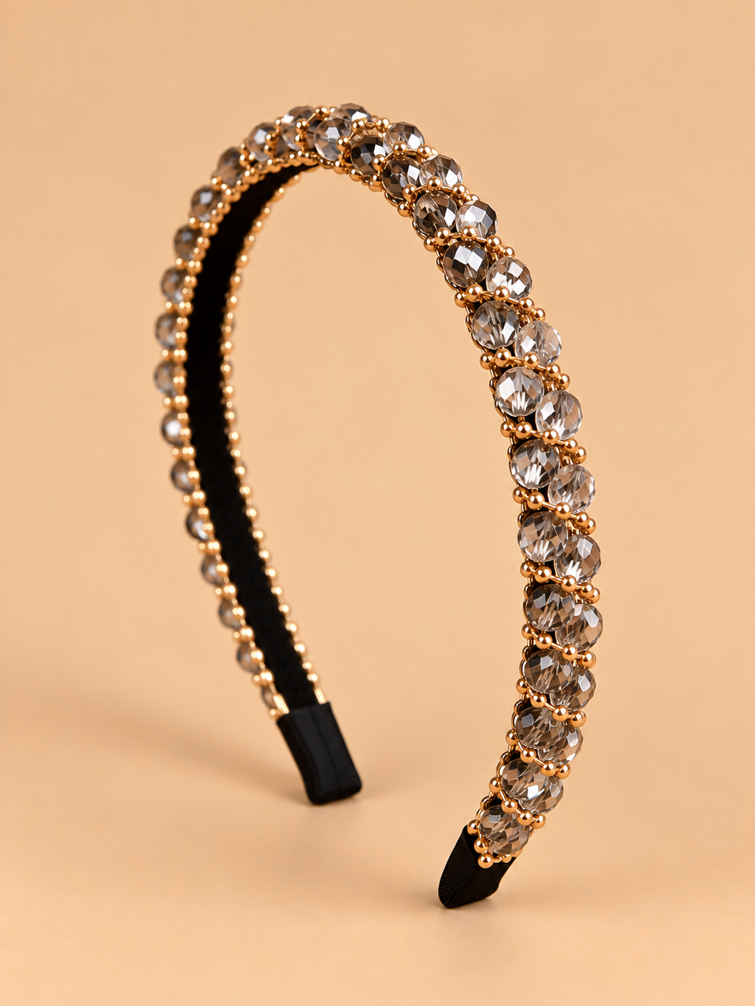 Smalle kristal haarband in smoky champagne met gouden details op beige achtergrond