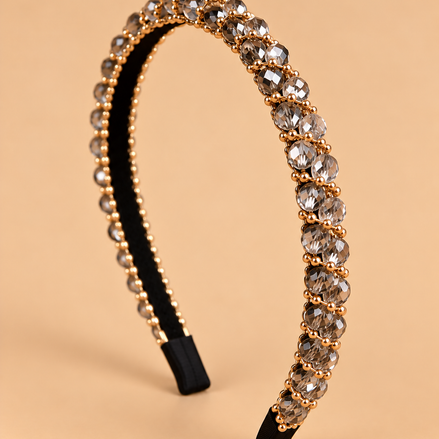 Smalle kristal haarband in smoky champagne met gouden details op beige achtergrond