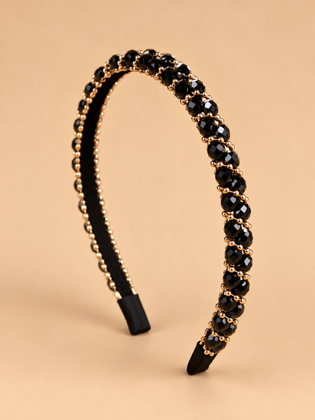 Smalle zwarte kristal haarband met gouden details op beige achtergrond