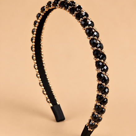 Smalle zwarte kristal haarband met gouden details op beige achtergrond