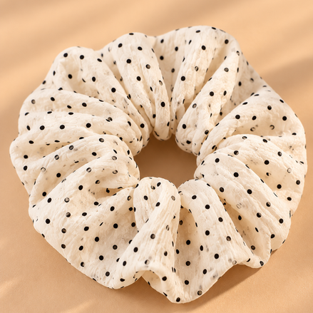 Crème scrunchie met zwarte stippen op beige achtergrond