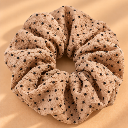 Lichtbruine scrunchie met zwarte stippen op beige achtergrond