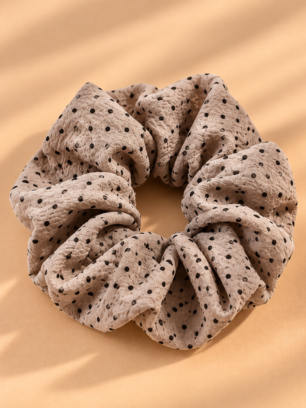 Taupe scrunchie met zwarte stippen op beige achtergrond