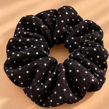 Zwarte scrunchie met witte stippen op beige achtergrond
