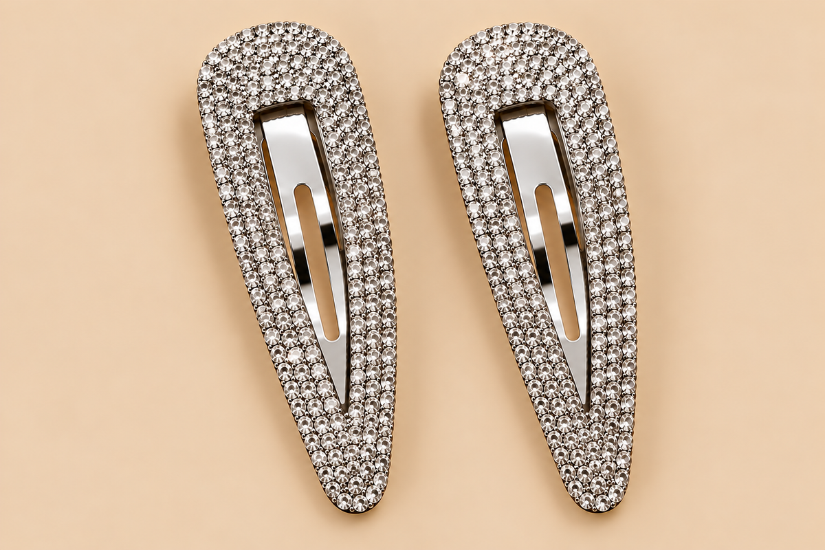 Set van twee zilverkleurige strass haarspeldjes op een egale beige achtergrond